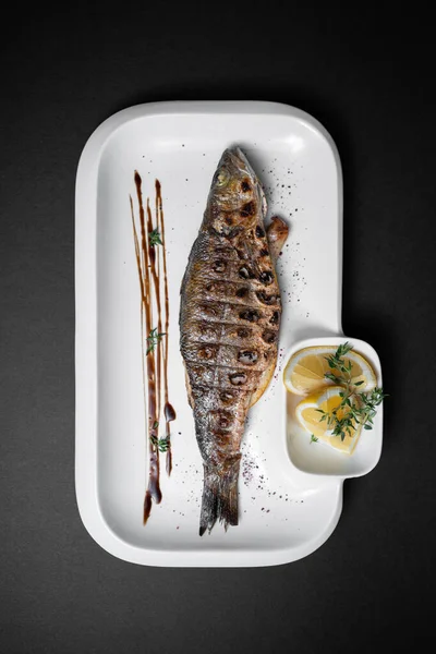 Siyah arka planda limonlu ızgara doldurulmuş balık levreği.