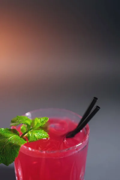 Nahaufnahme eines roten Erdbeer-Cocktailgetränks mit Minze im Glas auf grauem Hintergrund — Stockfoto