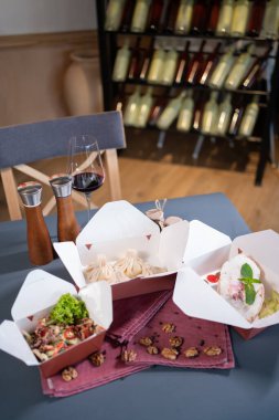 Kravat kağıdına yakın yiyecek kapları ve kafeterya masasında servis için yemek.