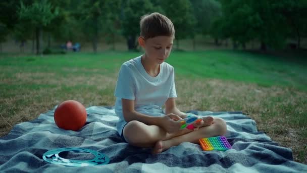 Kinderhände spielen mit einfachen Grübchen oder schieben Antistress-Spielzeug im Park im Freien — Stockvideo