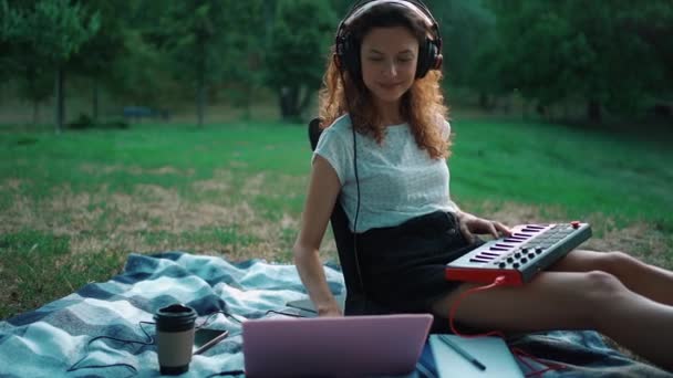 Χαρούμενη μουσικός κορίτσι παίζει midi συνθεσάιζερ πληκτρολόγιο και συνθέτουν μουσική εξωτερική — Αρχείο Βίντεο
