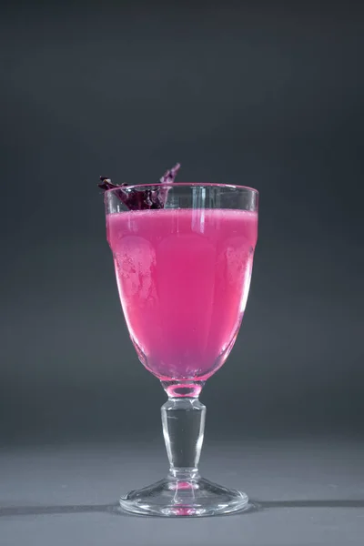 Bebida de cóctel rosa alcohol de lujo con albahaca en vidrio sobre fondo gris — Foto de Stock