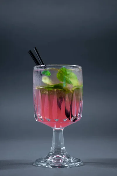 ピンクのレモネードにミントかローズのカクテルをグレーの背景にグラスに入れて — ストック写真