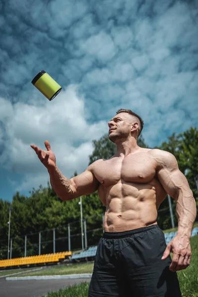 Muskulöser Bodybuilder-Rüde wirft Container mit Protein-Molkenpulver nach draußen — Stockfoto