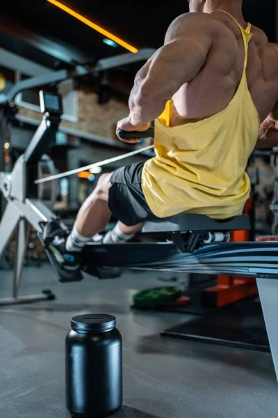 Proteína de soro de leite em pó em recipiente preto e musculação masculina exercitando no ginásio — Fotografia de Stock
