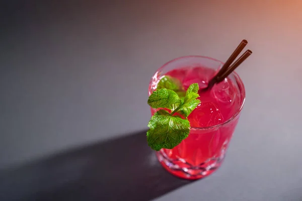 Nahaufnahme eines roten Erdbeer-Cocktailgetränks mit Minze im Glas auf grauem Hintergrund — Stockfoto