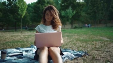 Parkta battaniyeli dizüstü bilgisayarla çalışan ya da çalışan güzel bir kadın.