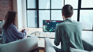 Mutlu çift evdeki oyun konsolunda kontrolörle video oyunu oynuyor.