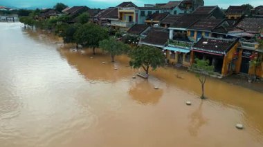 sel basmış şehir ya da kasaba, taşmış su ve çamura batmış binalar, şiddetli tropikal yağmur ve tayfundan sonra su altındaki köy, sokakta toprak oluşması, insansız hava aracı manzarası. Yüksek kalite 4k görüntü