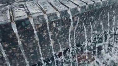 Taş çeşme duvarından aşağı akan su modern granit yüzeyde çağlayan temiz akarsular. Yüksek kalite 4k görüntü