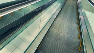 Modern, parlak yürüyen merdiven çağdaş binada aşağı doğru iniyor, metal merdiven basamakları içeri ulaşım perspektifi, pov. Yüksek kalite 4k görüntü