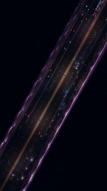 Modern yolda gece araba ve taşıma araçlarıyla uçmak, aydınlatmalı neon ışıklı modern fütüristik otoyolun ışıkları, tam yukarıda, hava aracı görüntüsü, 4k dikey video görüntüsü