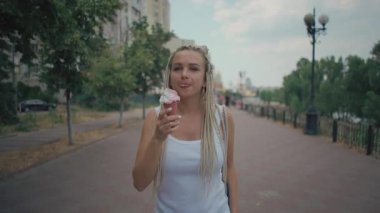 Afro örgülü genç bir kadın dışarıda dondurma yiyor.