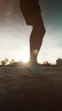 Gün batımı egzersizi sırasında deniz kıyısında ip atlayan vücut geliştiriciyi, güneş batarken okyanus kıyısında atlama halatıyla antrenman yapan sporcuları kardiyo egzersizi için dikey video 4k çekimleri. Yüksek kalite 4k görüntü