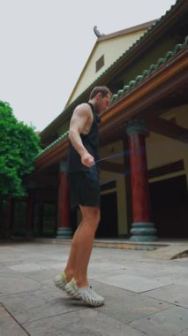 Genç erkek atlet atlama halatı egzersizi, spor yoğunluğu açık havada, adam halatla atlıyor, fitness gücü doğada, 4k dikey video. Yüksek kaliteli görüntüler