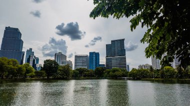 Göl ve gökdelen manzaralı modern yeşil park gölet suyunda şehir yansıması, Lumpini, Bangkok. Yüksek kalite fotoğraf