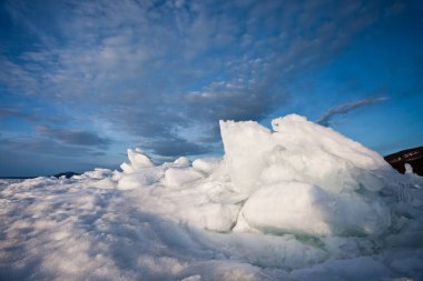 Güneşin aydınlattığı mavi gökyüzü üzerindeki buzlu, parlak mavi hummoklar Baykal manzarası.