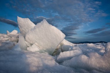 Buz vızıltıları süslü bir şekilde üst üste yığılır Baykal 'ın mavi turkuaz buzu ve güneş tarafından kutsanmış gökyüzü.