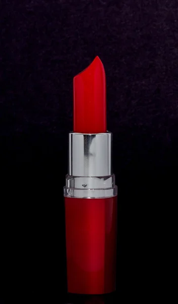 Rouge à lèvres rouge vif en tube rouge sur fond noir — Photo
