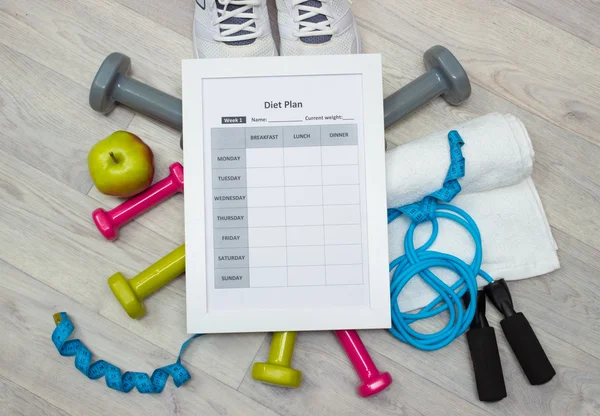 Various sport equipment with diet plan on wooden background