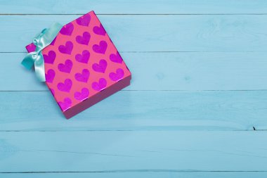 Hediye kutusu kalpleri ile pembe ve mavi arka plan üzerinde yay