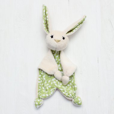 Hafif ahşap zemin üzerine bej ve yeşil oyuncak tavşan