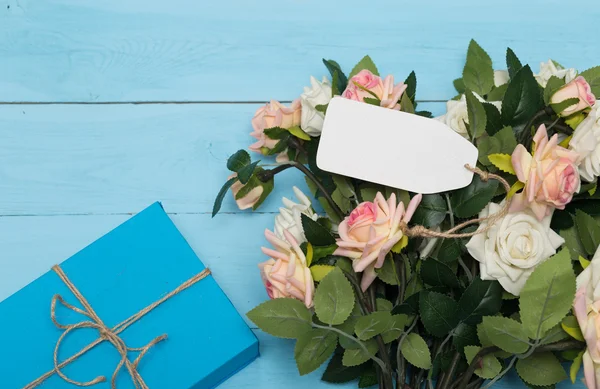 Carta bianca, fiori e regalo su sfondo blu legno — Foto Stock