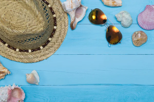 Muscheln, Hut und Sonnenbrille auf blauem Holzgrund — Stockfoto