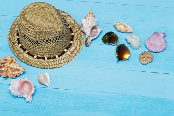 Muscheln, Hut und Sonnenbrille auf blauem Holzgrund — Stockfoto