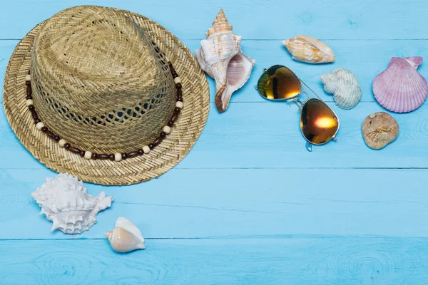 Muscheln, Hut und Sonnenbrille auf blauem Holzgrund — Stockfoto