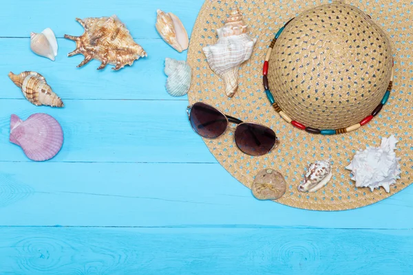 Conchas de mar, sombrero y gafas de sol sobre fondo de madera azul — Foto de Stock