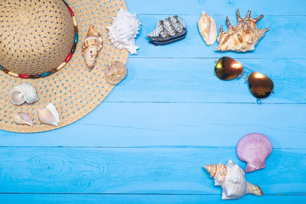 Sombrero de verano, conchas de mar, gafas de sol y barco sobre fondo azul — Foto de Stock