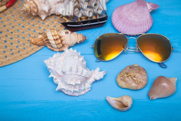Sommermütze, Muscheln, Sonnenbrille und Schiff auf blauem Hintergrund — Stockfoto