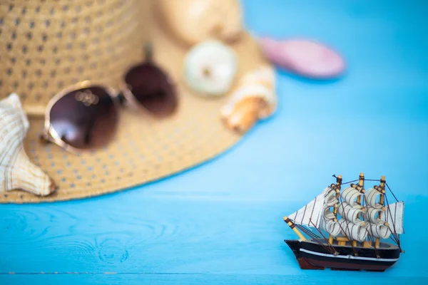 Spielzeugschiff, verschwommener Hut, Sonnenbrille und Muscheln auf dem Rücken — Stockfoto