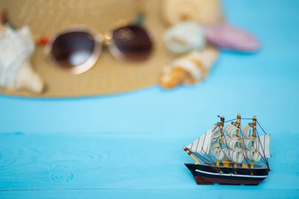 Spielzeugschiff, verschwommener Hut, Sonnenbrille und Muscheln auf dem Rücken — Stockfoto