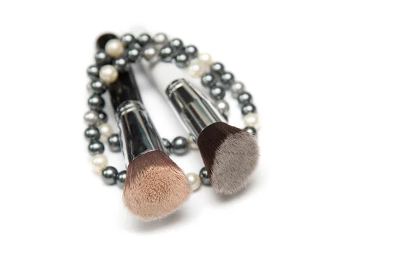 Collar de perlas y cepillo de maquillaje en él en primer plano — Foto de Stock