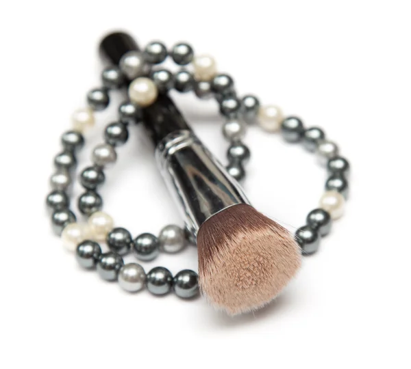 Collar de perlas y cepillo de maquillaje en él en primer plano — Foto de Stock