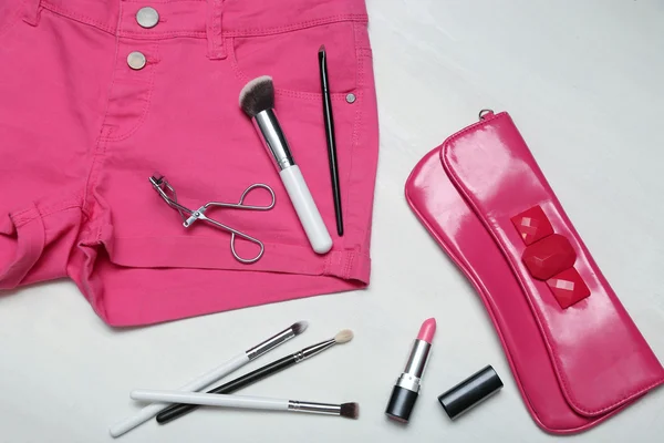 Sortierte Schminkutensilien auf rosa Jeans — Stockfoto