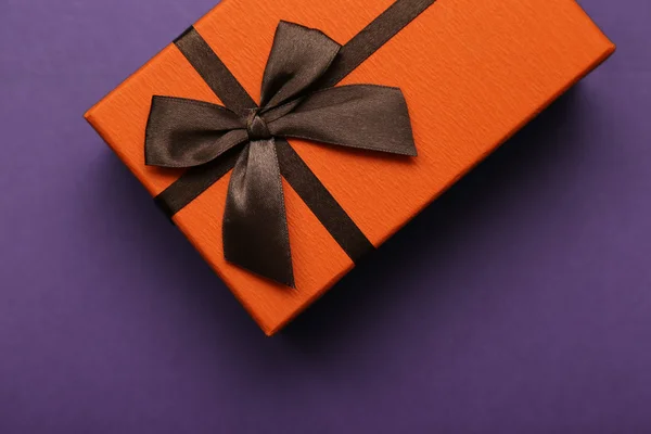 Orange Geschenkschachtel mit brauner Schleife auf lila Hintergrund Stockbild