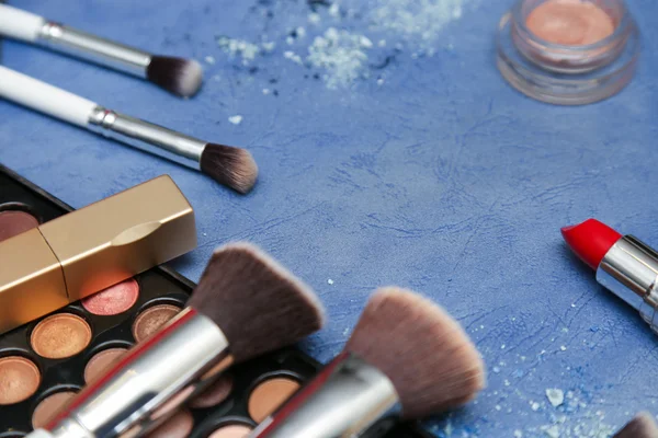 Kollektion von Make-up-Produkten auf blauem Hintergrund mit Copyspace Stockbild