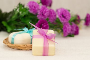 Two pieces of soap with a basket with a bow and flowers