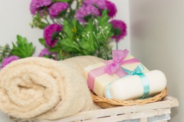 Two pieces of soap with a basket with a bows , flowers and towel