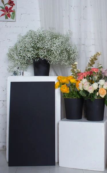 Tre boccole nere con fiori e scrivania nera — Foto Stock