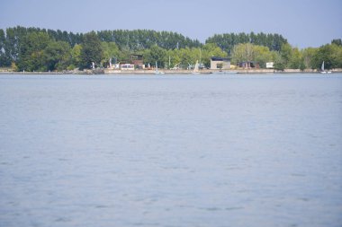 Sakin göl boyunca kayık ve ağaçlarla dolu liman şeridi