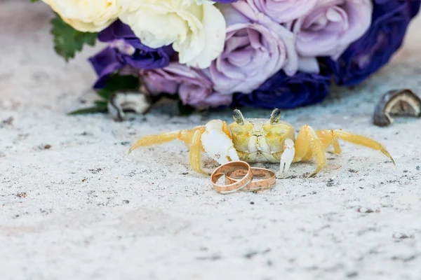 Fechar as alianças de casamento na praia com um caranguejo bonito amarelo — Fotografia de Stock