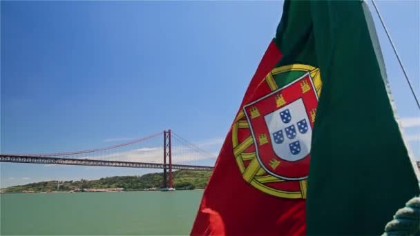 Португальский флаг на корабле на фоне моста 25 апреля и статуи Иисуса — стоковое видео