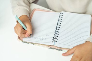 Not defterine yazan genç kız manzarası. Ödev yapan ya da yazma becerisi geliştiren çocukların elleri. Eğitim kavramı, erken öğrenim, okul aktiviteleri, çocukluk gelişimi.