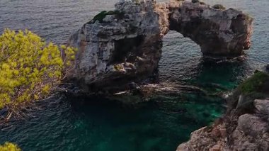 İspanya, Mallorca, Cala Santany yakınlarındaki dramatik deniz kemeri Es Pontas. Turkuaz su, seyahat, doğa veya macera temalarından yükselen ikonik kıyı kaya oluşumu. 