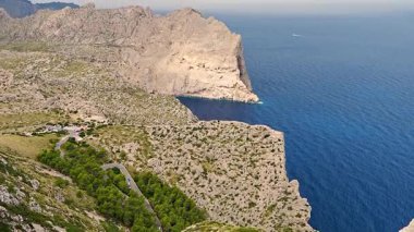 Mallorca adasındaki ikonik Formentor deniz fenerine giden kıvrımlı dağ yolu. Çarpıcı kıyı manzarası ve dramatik manzara. Seyahat, turizm ve macera temaları için ideal.