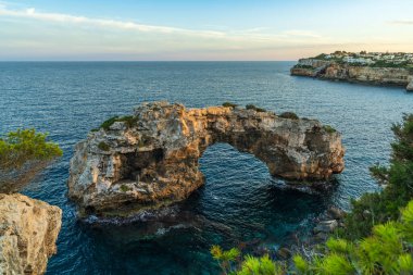 Mallorca, Cala Santanyi 'de altın gün batımında parlayan doğal taş kemer. Dramatik kaya oluşumlu huzurlu Akdeniz sahnesi.